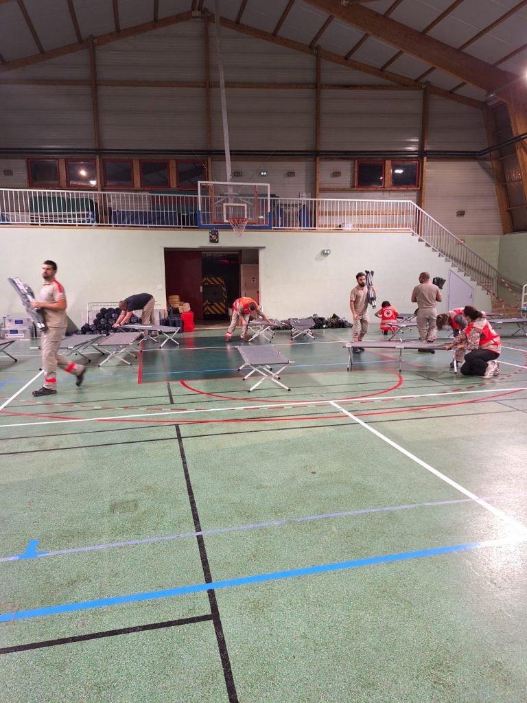 Installation des lits de camp par la Croix Rouge au gymnase Favier - Protéger et Agir